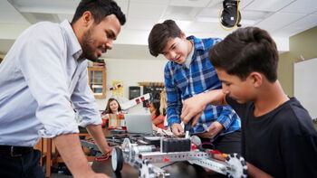 Elever og lærer utfører og en fjernstyrt robot i klasserommet. Foto.
