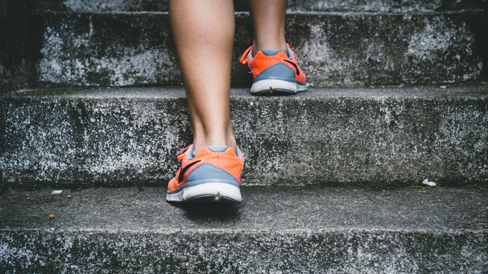 Feet in athletic shoes ascending a stone staircaise