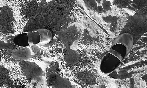 A pair of childrens shoes in the sand. Foto