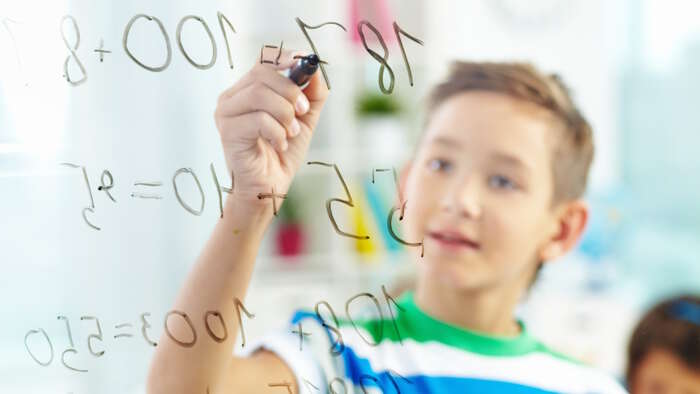 boy doing math problems on white board