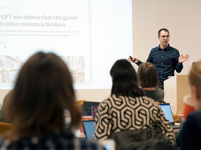 Presenter in classroom, students in front, seen from the back. 