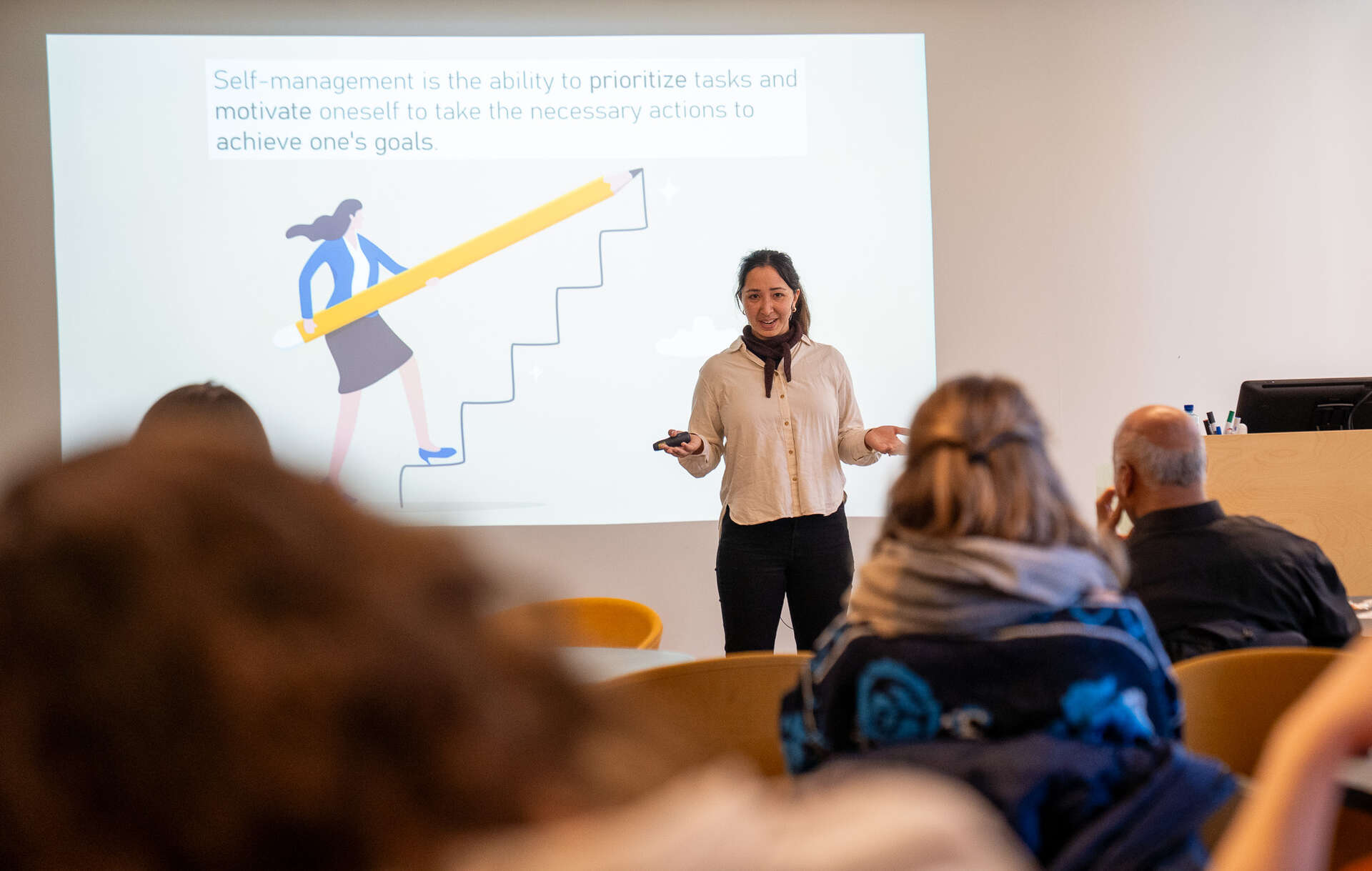 Woman giving a talk in front of a classroom.