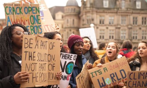 Ungdom med plakater demonstrerer for klimahandling  (foto: C. Shaw /Unsplash).