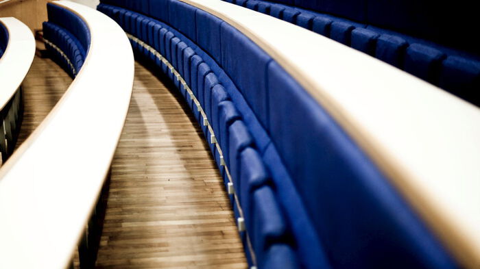 Tomt auditorium med mange rader av blå, nedfellbare stoler.