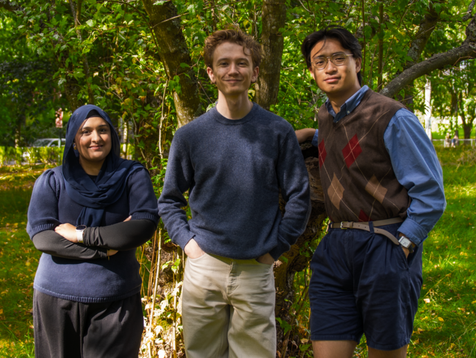 Idea Studentteam består av tre studenter, som står utendørs foran et tre.