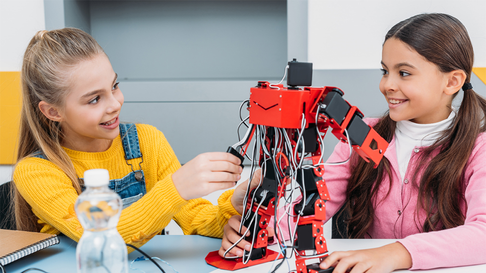 Two young girls working on engineering project with robot made of lego. Illustration photo.