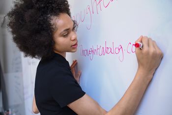 Teacher writing on whiteboard with red marker