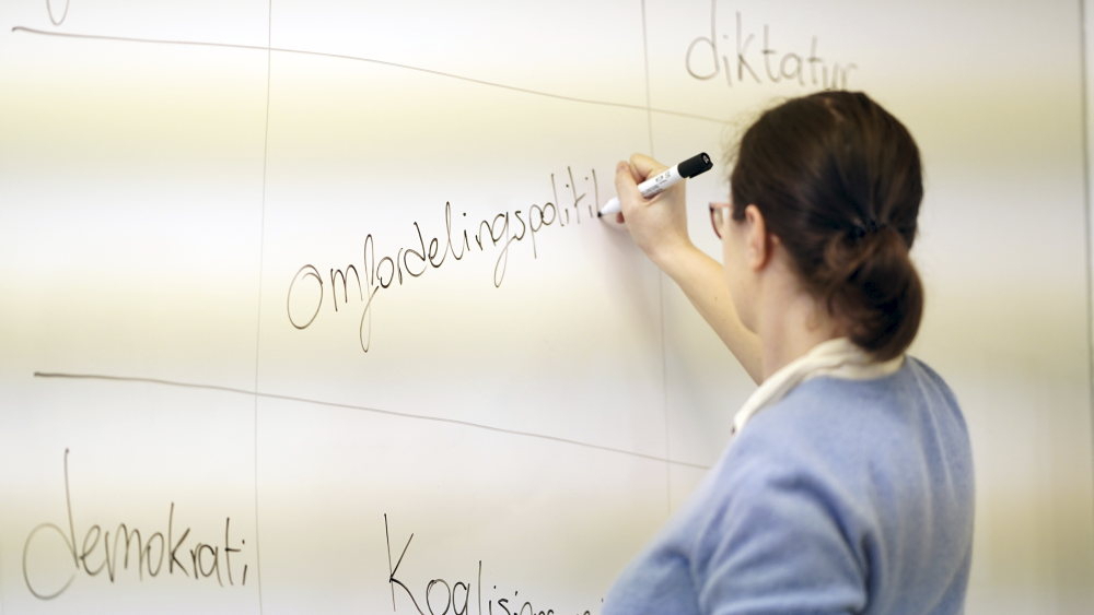 Lærer skriver på tavla. Illustrasjonsfoto.
