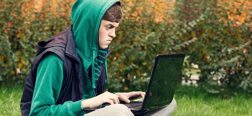 gutt i hettegenser jobber på laptop. illustrasjonsfoto: colourbox.