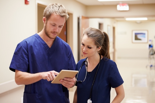 Two hospital employees looking at a digital deveice. Photo.
