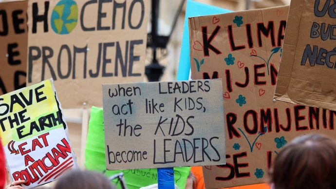 foto av paroler og plakater med slagord for klimaet på engelsk. "when leaders act like kids, the kids become leaders" står det på den mest sentrale i bildet.