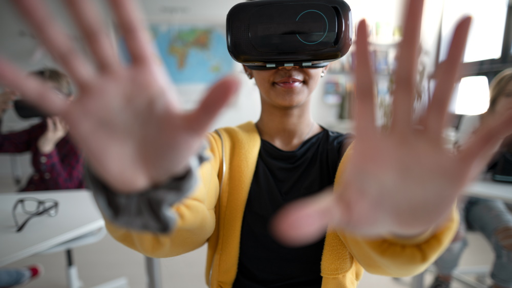 Ungdomsskolejente med VR-briller på. Holder hendene opp foran seg.