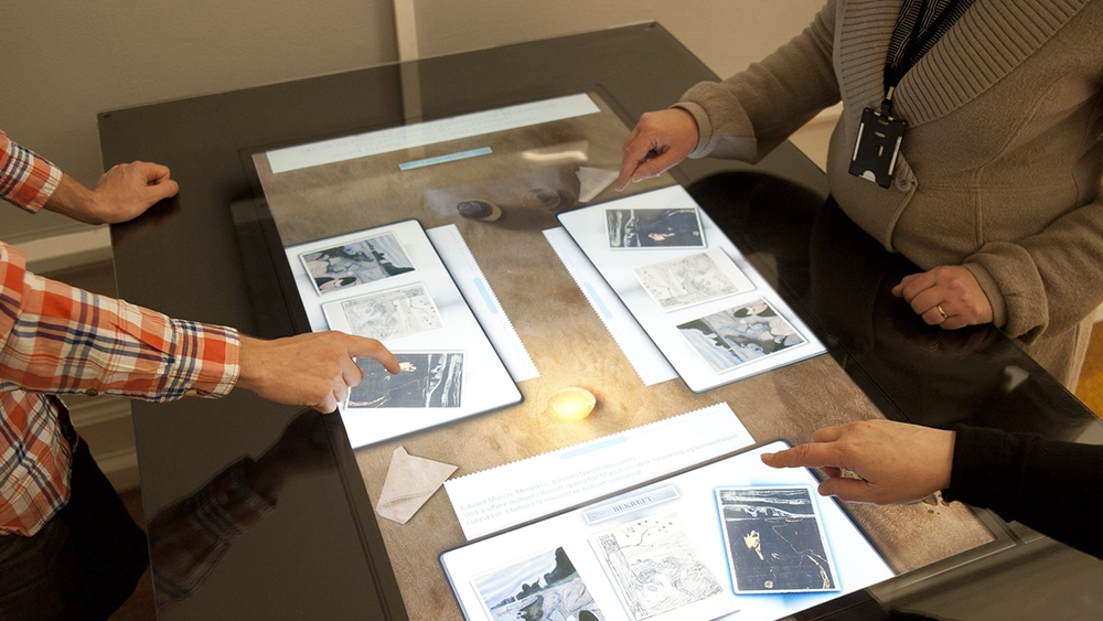 Tre personer bruker et multi-touch bord med Munch-motiver som oppgaver.