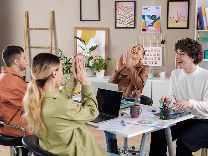 En gruppe masterstudenter i pedagogikk ved Universitetet i Oslo arbeider med en gruppeoppgave. Det er to kvinner og to menn, og de ler. To av dem klapper med hendene.