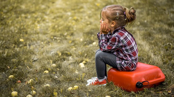 Little girl sitting on a canister in a field of grass