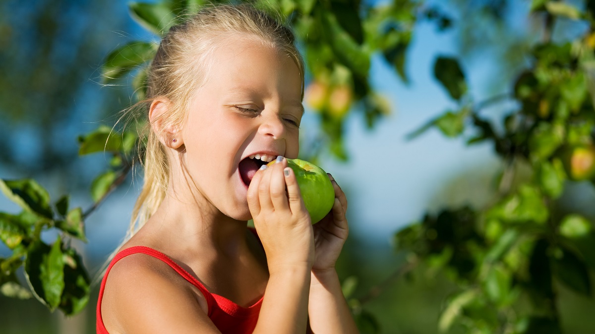 illustrasjonsfoto av jente som biter i et eple, og lager grimaser 