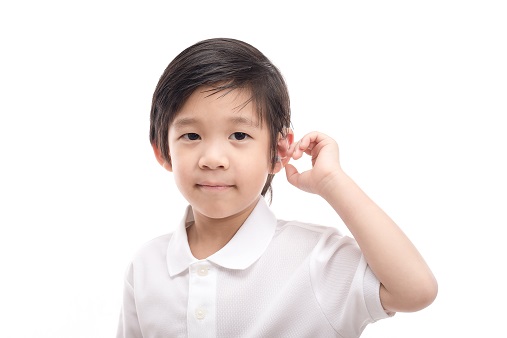 gutt med høreapparat som tar seg på øret