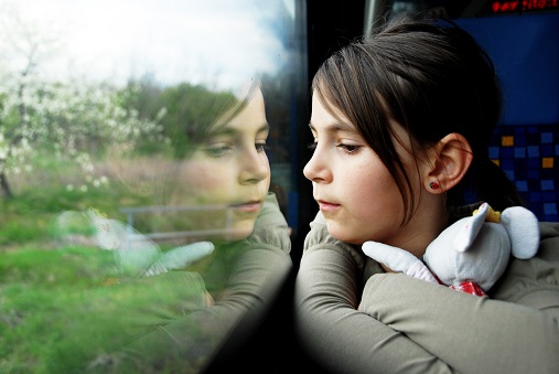 Bilde av en ung jente som ser ut av et togvindu