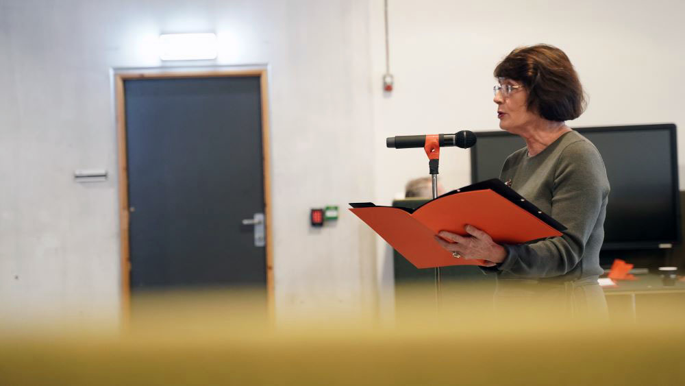 Dekan Rita Hvistendahl i profil står bak en mikrofon og snakker.