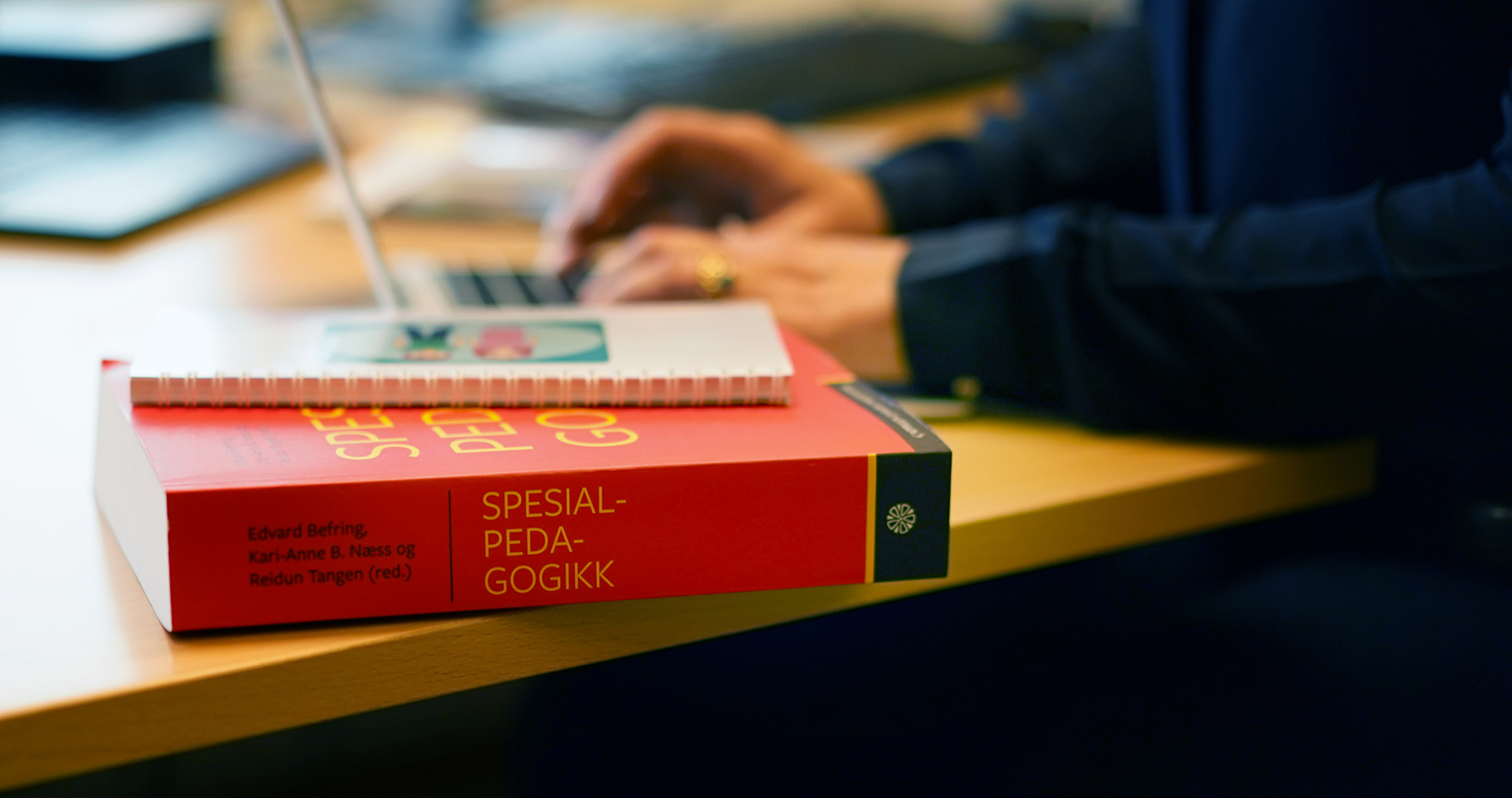 Bok om spesialpedagogikk ligger på skrivebord. 