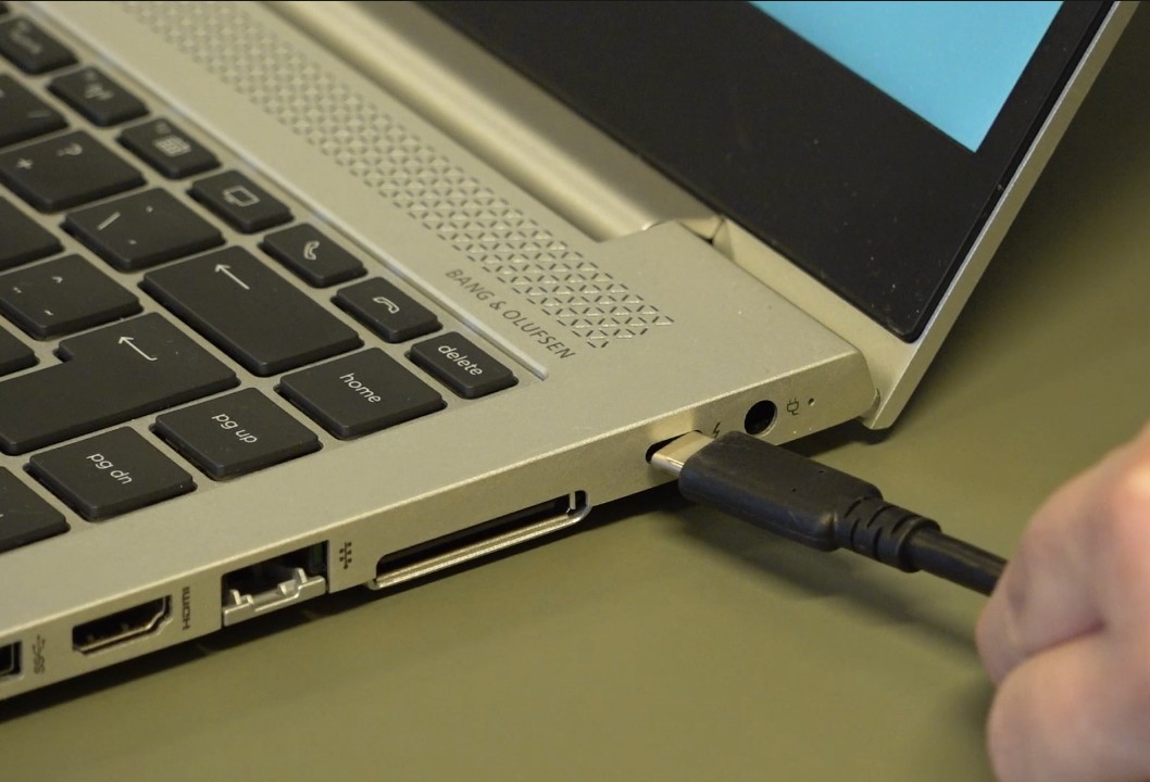 Close-up av laptop og usb-c kable som kobbles til. Foto. 