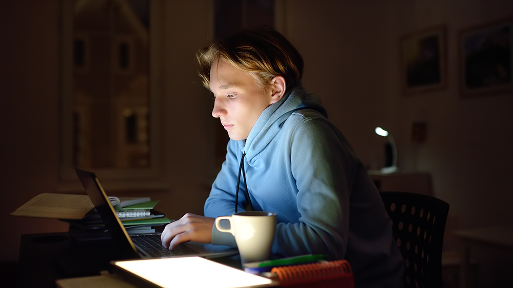 Illustration photo of concentrated young man working late night with laptop and tablet.