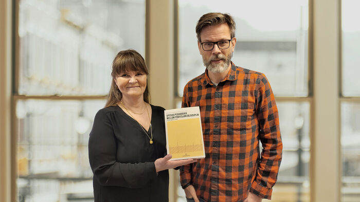 To forskere viser stolt frem boken de har skrevet